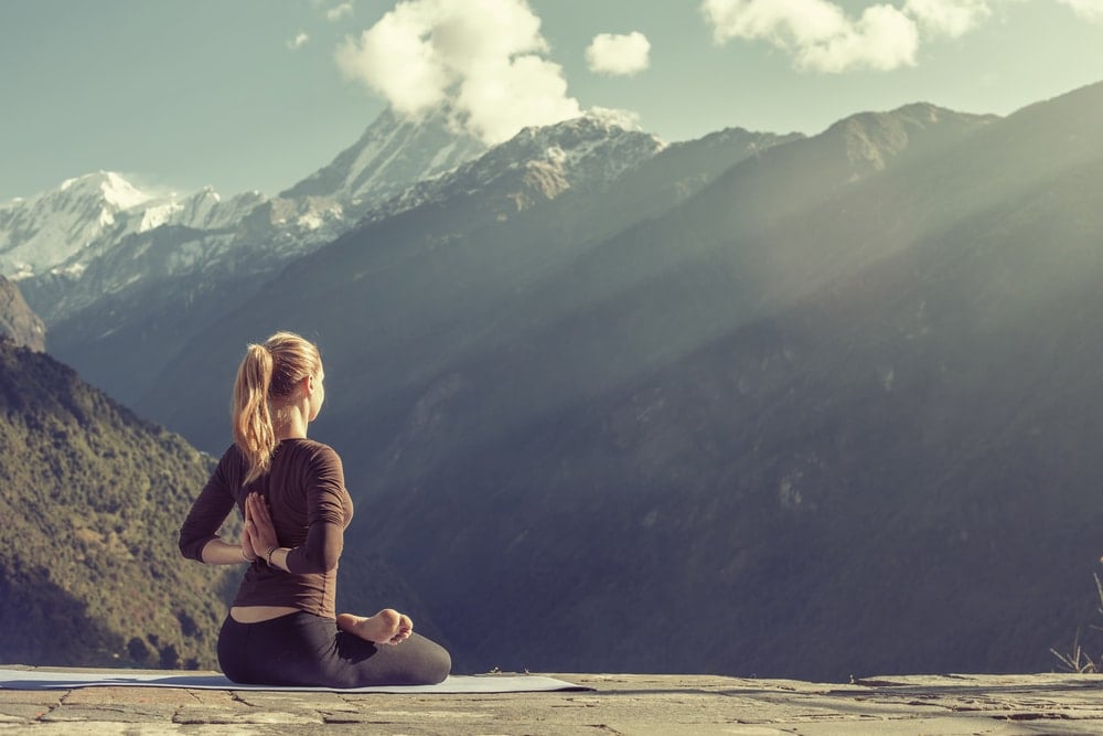 A working traveller doing yoga in the mountains