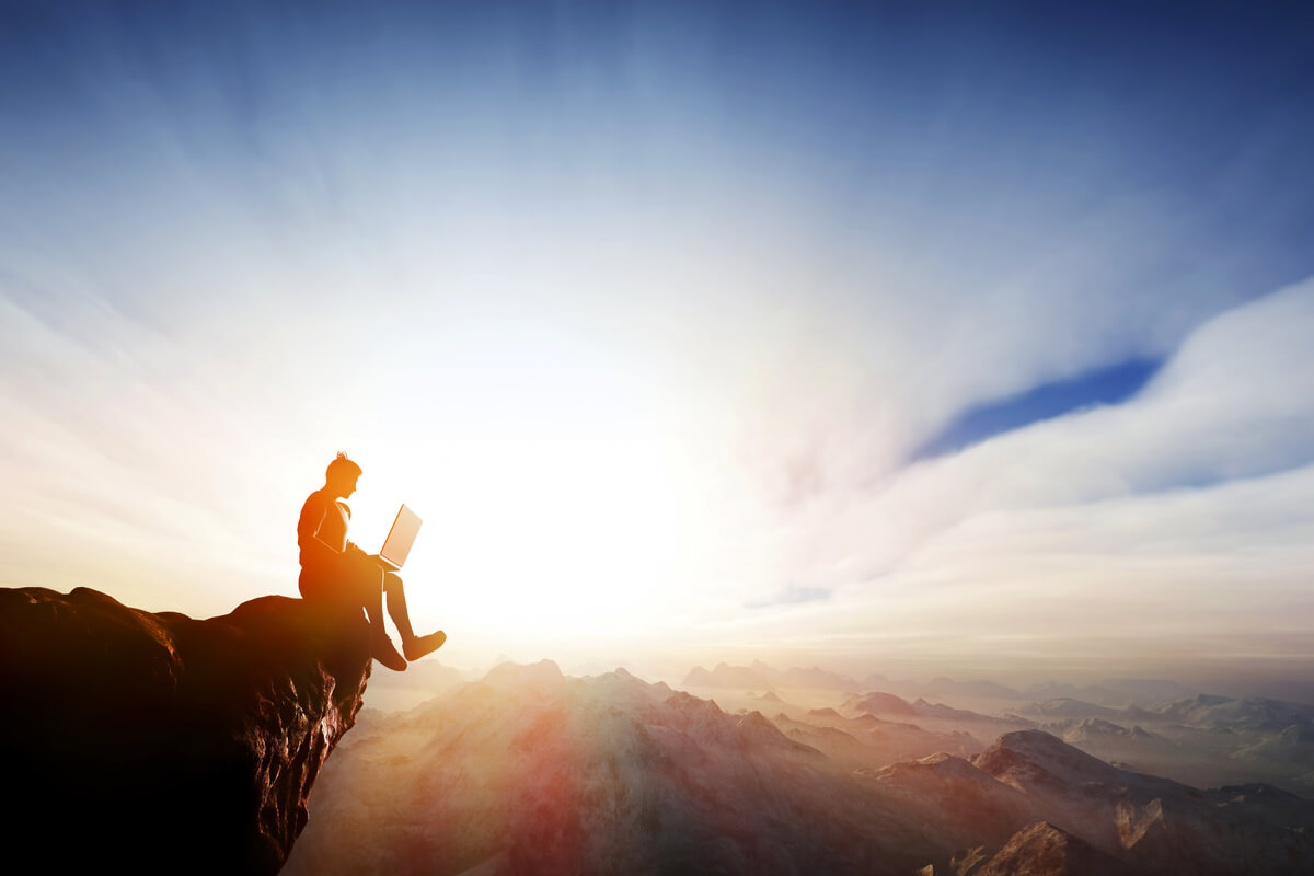 guy sitting on a cliff edge with computer