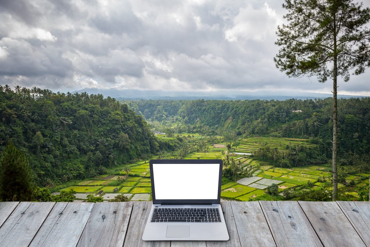 computer on a table facing a valley view