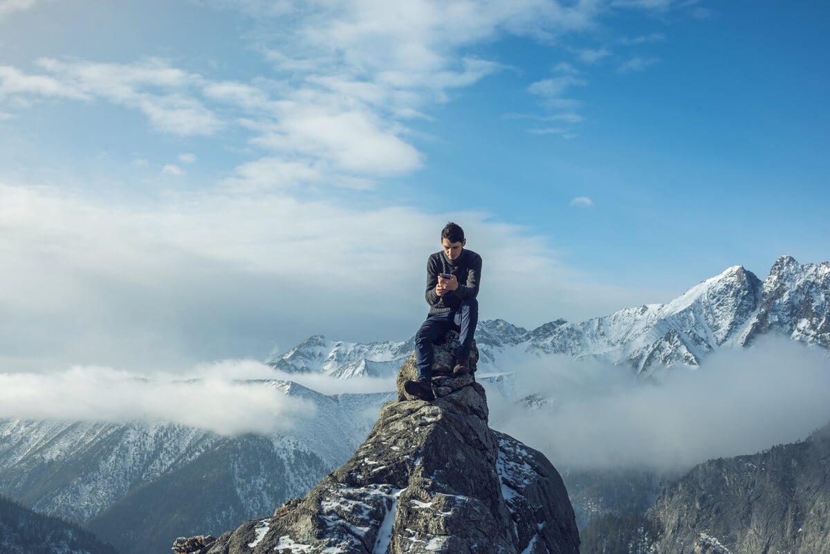 A traveller makes a phone call from a mountaintop