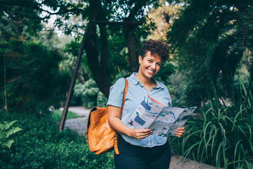 solo female traveller looking at a map and smiling at the camera