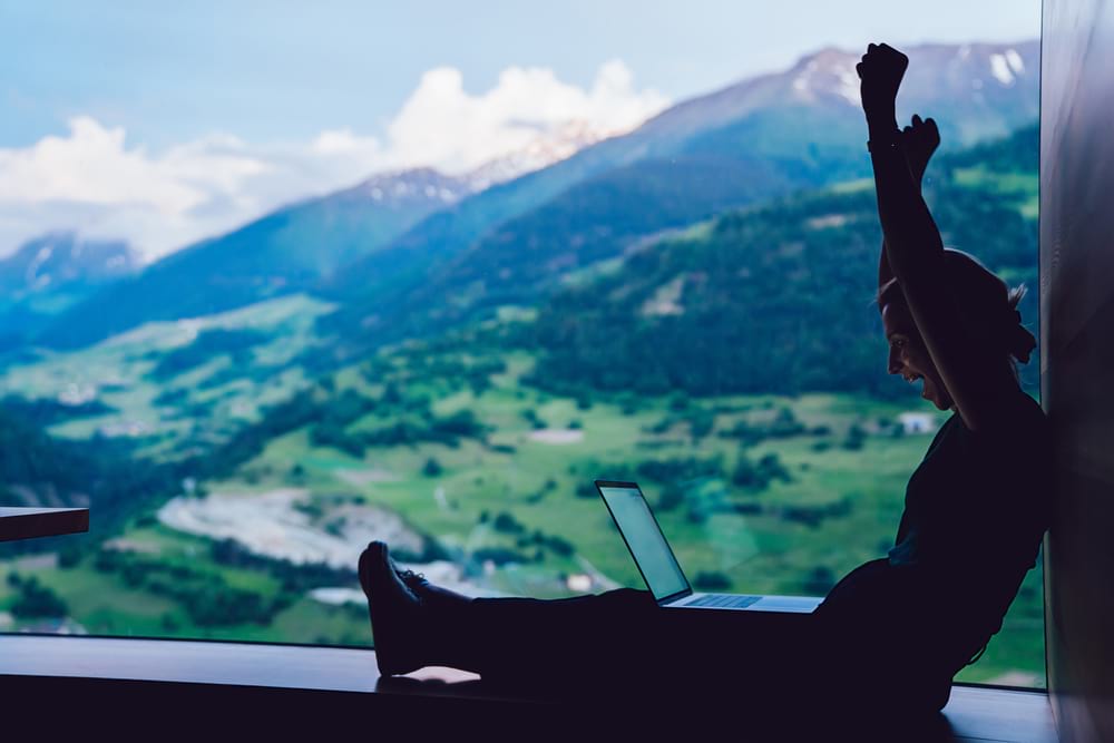 digital nomad in front of mountains looking happy